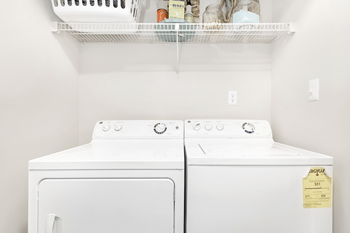 Two white dryers are in a laundry room.